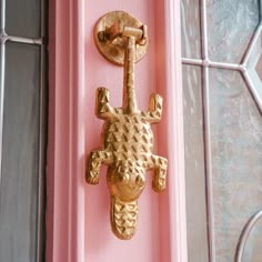 a gold door handle on a pink door