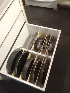 an open drawer filled with lots of plates and utensils next to a sink