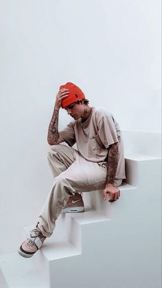 a man sitting on top of a white stair case wearing a red hat and khaki pants