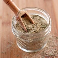 a jar filled with some kind of stuff on top of a wooden table next to a spoon