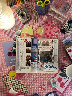 an open book sitting on top of a table covered in papers and other items next to a camera