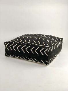 a black and white pillow with an arrow pattern on the front, sitting on a white surface