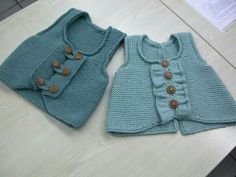 two knitted sweaters with buttons on the front and back, one in blue