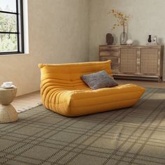 a living room filled with furniture and a rug on top of a wooden floor next to a window