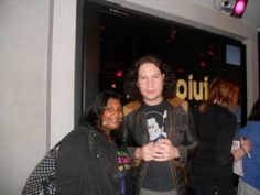 two people standing next to each other in front of a sign that says quiliu