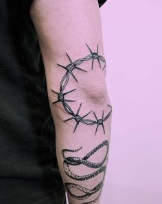 a man's arm with barbed wire on it and a snake wrapped around the wrist