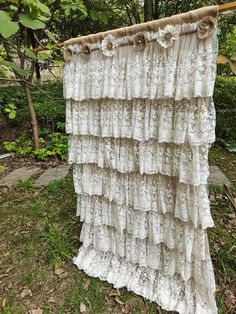 an old lace curtain hanging on a clothes line in front of some trees and bushes