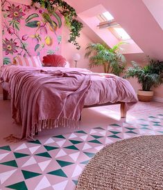 a bedroom with pink walls and green plants on the wall next to it is decorated in pastel colors