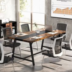 a table with chairs and a laptop on it in front of a large screen monitor