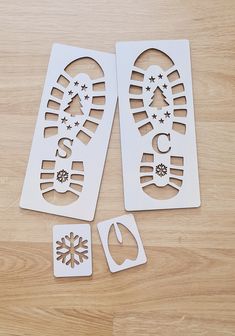 two white cut outs with snowflakes on them sitting on top of a wooden table