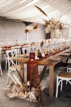 the table is set up with white chairs and tall centerpieces on each side