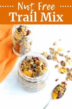 two jars filled with trail mix on top of a white table next to an orange napkin