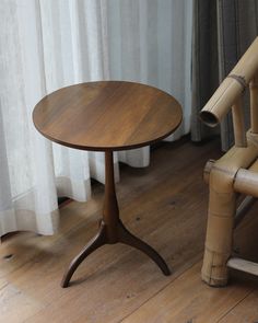 a wooden table sitting on top of a hard wood floor next to a bamboo chair