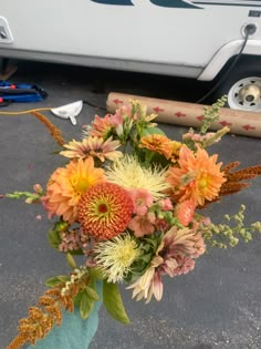 a bouquet of flowers sitting on the ground next to a white van and some tools