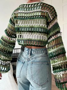 a woman standing in front of a bed wearing jeans and a cropped top with crocheted sleeves