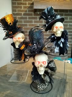 three skulls with hats on display in front of a brick wall and wooden flooring