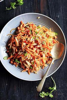 a white plate topped with shredded carrots and broccoli next to a spoon