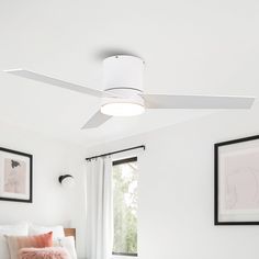 a white ceiling fan in a bedroom with pictures on the wall above it and a bed