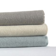 three different colors of blankets stacked on top of each other in various sizes and shapes