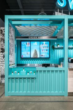 a store front with blue walls and white counter tops that has two televisions on the wall