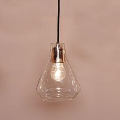 a clear glass light bulb hanging from a black cord on a pink wall with a white flower in the center