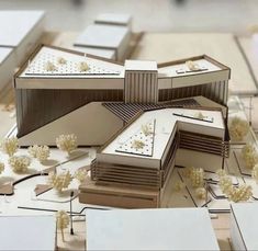 an architectural model of a building surrounded by smaller buildings and flowers on the ground in front of it