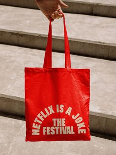 a person holding a red bag that says netflix is a joke the festival on it