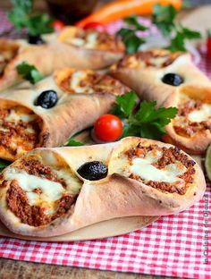 pizza rolls with olives, tomatoes and parsley on a checkered tablecloth