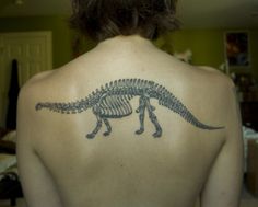 a person with a tattoo on their back that has a dinosaur skeleton on it's back