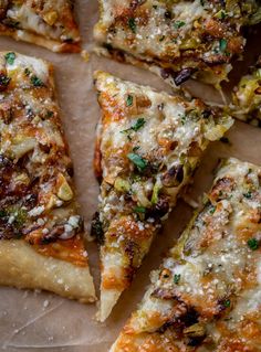 several slices of pizza sitting on top of a piece of parchment paper covered in cheese and toppings