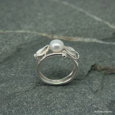 Handcrafted sterling silver, art nouveau style ring with single freshwater pearl. Created in our own studio In Cornwall A beautiful, flowing art nouveau style pearl ring with silver leaves and vine wrapped around two silver wire bands. The leaves have a satin finish and the silver bands are highly polished UK finger sizes  J to T Other sizes  request  All my jewellery comes in a presentation gift box.  All my designs are hand made and no two are exactly the same.   Thank you for your time. Please note that international shipping fees do not include possible custom charges for your country and you will be solely responsible for payment of these charges.  We are required by law to fully disclose the contents and value of the items in your package for Customs purposes.  Your local customs off Elegant Handmade White Gold Flower Ring, Unique Sterling Silver Pearl Ring For Wedding, Elegant Handmade Pearl Ring For Wedding, Elegant Handmade Pearl Promise Ring, Handmade Elegant Sterling Silver Pearl Ring, Handmade Sterling Silver Pearl Ring, Unique Handmade Pearl Ring For Wedding, Unique Handmade Pearl Wedding Ring, Unique Handmade Pearl Promise Ring