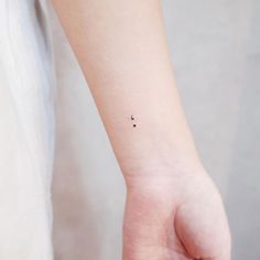 a small tattoo on the wrist of a woman's left hand, with two dots