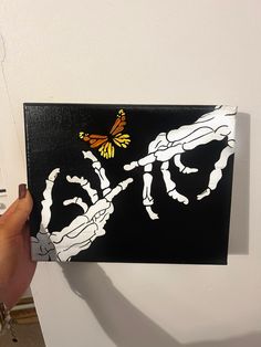 a person holding up a piece of art with a butterfly on it