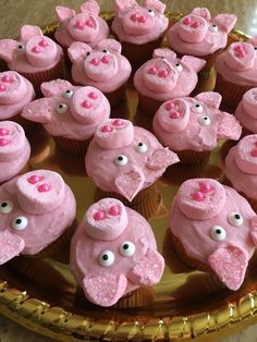 cupcakes with pink frosting decorated as pigs on a gold platter, ready to be eaten