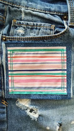 the back pocket of a pair of jeans with an embroidered patch on it and torn edges