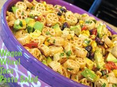 a purple bowl filled with pasta salad on top of a counter