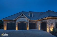 a large brick house with two garage doors and lights