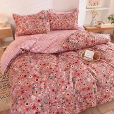 a bed with pink flowers on it in a room next to a table and lamp