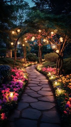 a pathway that is surrounded by flowers and lit up with lanterns in the night time