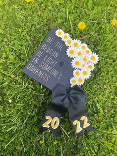 a graduation cap with daisies on it laying in the grass