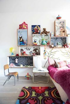 a room filled with lots of pictures and toys on the wall next to a bed