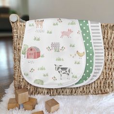 a basket with wooden blocks on top of it next to a blanket and toy animals