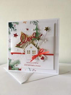 a christmas card with an ornament on the front and a house in the back