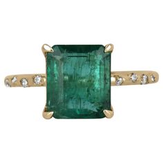 Displayed is a modern emerald and diamond solitaire engagement ring/right-hand ring in 14K yellow gold. This gorgeous solitaire ring carries a 2.60-carat emerald in a four-prong setting. Fully faceted, this gemstone showcases excellent shine. The emerald has very good clarity with minor flaws that are normal in all genuine emeralds. Diamonds are sprinkled into the gold shank. Minimalist and beautiful. Setting Style: Prong/Bezel Setting Material: 14K Yellow Gold Main Stone: Emerald Shape: Emerald Cut Weight: 2.60-Carats Color: Dark Green Luster: Very Good Origin: Zambia Treatments: Natural, Oiling Secondary Stone: Diamond Shape: Brilliant Round Weight: 0.08-Carats (Total) Total Diamonds: 8 Eye Clarity: VS Color: H-I Luster: Excellent Treatments: Natural Estimated Retail Value: $9,600.00 USD Right Hand Rings, Hand Ring, Diamond Solitaire Engagement Ring, Jewelry Rings Engagement, Solitaire Engagement, Solitaire Engagement Ring, Diamond Solitaire, Bezel Setting, Solitaire Ring