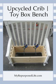 the upcycled crib toy box bench is made from wood and has two blue scissors in it