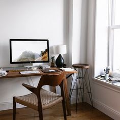 a computer monitor sitting on top of a wooden desk next to a lamp and chair