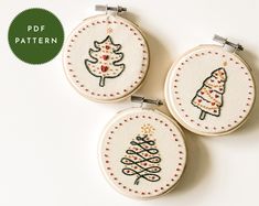 three hand embroidered christmas trees on white fabric