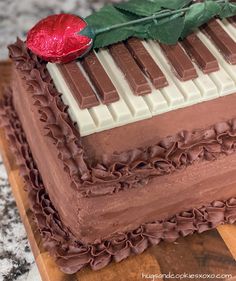 a cake with chocolate icing and a rose on top that is shaped like a piano