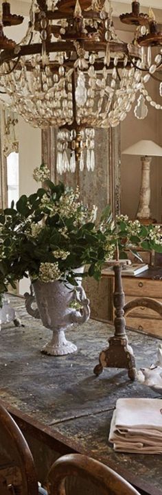 a chandelier hanging from the ceiling above a table with flowers in vases