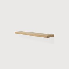 a wooden shelf sitting on top of a white wall in front of a white background